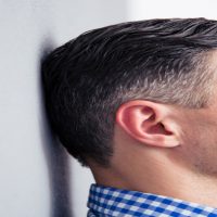 Wenn Glaubenssätze das Burnout Risiko massiv erhöhen Mann steht mit geschlossenen Augen an einer Wand