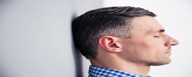 Wenn Glaubenssätze das Burnout Risiko massiv erhöhen Mann steht mit geschlossenen Augen an einer Wand